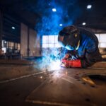 Close up view of worker welding metal construction in industrial workshop.